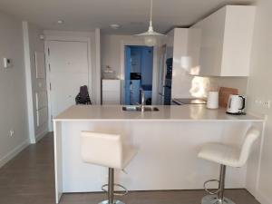 a kitchen with a white counter and two bar stools at Apartamento Duna Beach in Torrox