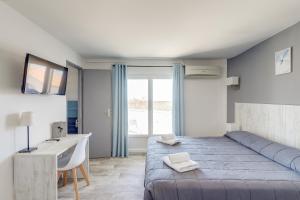 a bedroom with a bed and a desk and a window at Hotel Les Palmiers En Camargue in Saintes-Maries-de-la-Mer