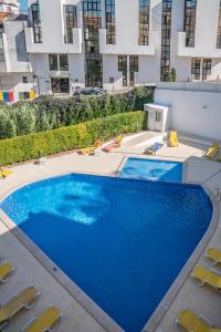 ein großer blauer Pool mit Stühlen und ein Gebäude in der Unterkunft Garden Hill Apartment in Albufeira