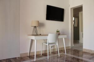 einen weißen Schreibtisch mit einem Stuhl und einem TV an der Wand in der Unterkunft B&B Le Terrazze in Terrasini