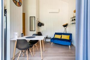 une chambre avec une table, des chaises et un canapé bleu dans l'établissement Les minis homes du Bugey - Eco-lodge City, un refuge en hyper centre, à Ambérieu-en-Bugey