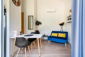 a room with a table and chairs and a blue couch at Les minis homes du Bugey - Eco-lodge City, un refuge en hyper centre in Ambérieu-en-Bugey