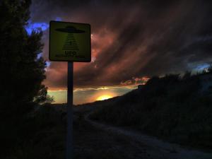 una señal en un camino con la puesta de sol en el fondo en Hotel Cueva Tardienta Monegros-Adults Only, en Tardienta