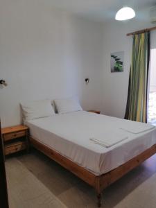 a bedroom with a bed with white sheets and a window at Jason Rooms & Studios in Keratokampos