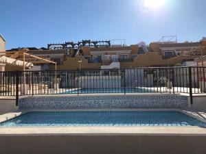 a swimming pool with a fence and some buildings at Bungalow Arenales del Sol, Alicante in Arenales del Sol