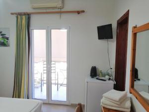a bedroom with a sliding glass door with a balcony at Jason Rooms & Studios in Keratokampos