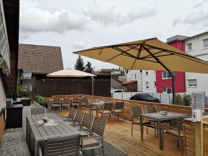 eine Terrasse mit Tischen, Stühlen und einem Sonnenschirm in der Unterkunft Brauerei-Gasthof Reichsadler in Mögglingen