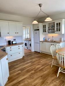 una cucina con armadietti bianchi e pavimenti in legno di Doughbeg Beach Cottage a Mulranny