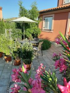 eine Terrasse mit einem Tisch und einigen Pflanzen und einem Sonnenschirm in der Unterkunft VILLA ANCORA MEDULIN in Medulin