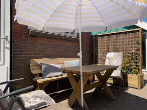 a picnic table with an umbrella on a patio at Oostvoornsch Gastenverblijf in Oostvoorne