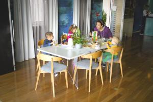 a woman sitting at a table with three children sitting at it at Apartments Villa Azzurra Bol in Bol