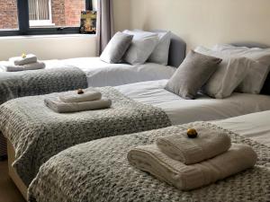 a room with three beds with towels on them at Vikings Two Bedroom Apartment With Free Parking. in York