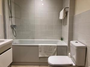 a bathroom with a tub and a toilet and a sink at Vikings Two Bedroom Apartment With Free Parking. in York