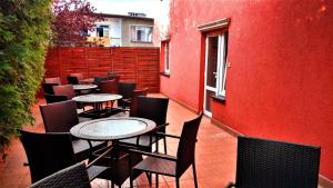 eine Terrasse mit Tischen und Stühlen und einer roten Wand in der Unterkunft KLIWER MIĘDZYZDROJE in Misdroy
