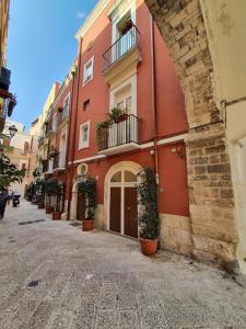 a red building with potted plants on a street at Arco Della Neve Guest House in Bari