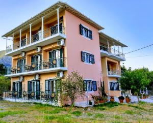 a pink building with black windows and balconies at STUDIOS LEFTERIS in Nydri