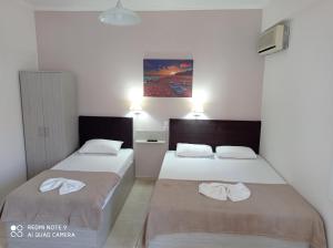 two beds in a room with white walls at Teo Rooms in Paralia Katerinis