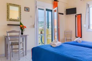 Habitación con 2 camas, mesa y ventana en Pension Soula, en Skopelos Town