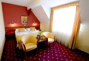 pokój hotelowy z łóżkiem i dwoma krzesłami w obiekcie Hotel Tilia w mieście Pezinok