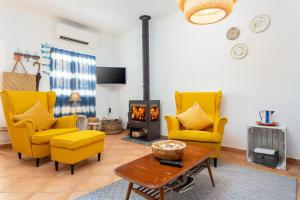 uma sala de estar com cadeiras amarelas e uma lareira em Casa Lagosta em Olhão