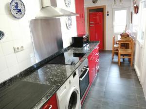 La cuisine est équipée de placards rouges et d'un four avec plaques de cuisson. dans l'établissement Ático en Cimadevilla Mirando al Mar, à Gijón 8 autres photos