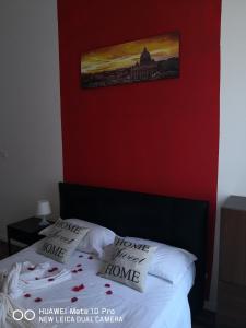 a bedroom with a red wall and a bed with pillows at St. Peter's Luxury House in Rome