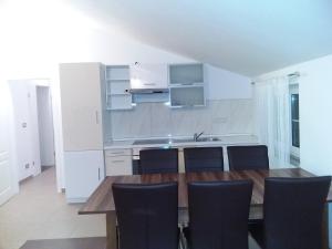 cocina con mesa de madera y sillas negras en House apartments Ariamare, en Poreč