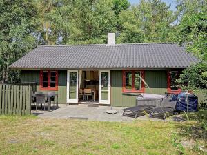 a green cottage with a table and chairs in a yard at 6 person holiday home in Nex in Snogebæk