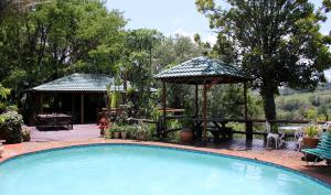 een zwembad met een prieel en een patio bij The Sabie Town House Guest Lodge in Sabie