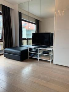 a living room with a television and a black leather couch at Les oyats in Nieuwpoort