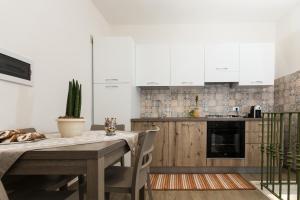 cocina con mesa de madera y armarios blancos en Case Vacanza Le Maioliche en Marsala