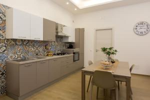 una cocina con armarios blancos y una mesa con sillas. en Case Vacanza Le Maioliche en Marsala