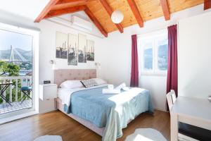 a white bedroom with a bed and a balcony at Orsan Residence in Dubrovnik