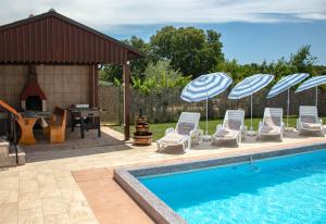 a group of chairs and umbrellas next to a pool at Holiday Home Darko in Svetvinčenat