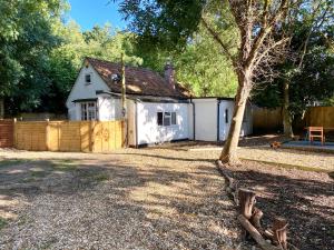 a white house with a fence and a tree at Holly Tree Cottage - 3 bedrooms and large garden with optional glamping double outside in Lymington