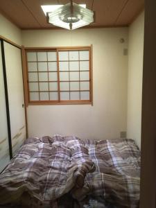 ein unmaskiertes Bett in einem Zimmer mit Fenster in der Unterkunft SUMIDA in Osaka