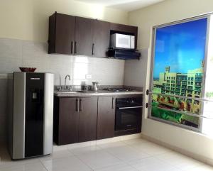 a kitchen with a stainless steel refrigerator and a window at APARTAESTUDIOS AMOBLADOS ARBOLEDA DE CADIZ in Ibagué
