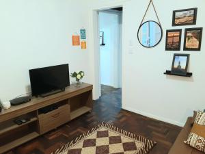 Una sala de estar con un televisor de pantalla plana en un centro de entretenimiento. en Amplo, aconchegante e pertinho de tudo, en Porto Alegre