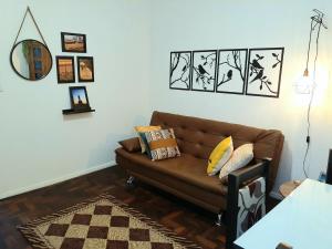 a living room with a brown couch and pictures on the wall at Amplo, aconchegante e pertinho de tudo in Porto Alegre