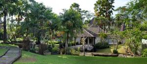 a house with palm trees in a yard at Ayurvedagram Bali - Wellness & Retreat Resort in Ubud