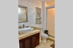 een badkamer met een wastafel, een toilet en een spiegel bij Tu DEPA en el Paraíso Cancún 2 in Cancun