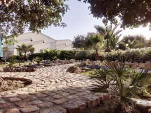 un sentiero in pietra in un giardino con piante di I 5 SENSI a Marina di Modica