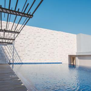 a swimming pool in front of a white brick wall at Aveta Hotel Malioboro in Yogyakarta