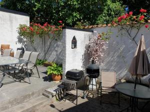 un patio con parrilla, mesas y sillas en Adelsgatan 36 lägenhetshotell, Gotland Living and Meeting en Visby