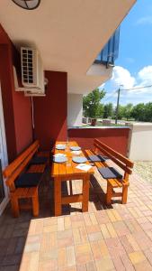 eine Gruppe von Holztischen und -bänken auf einer Terrasse in der Unterkunft Aqua Apartman in Tiszaújváros