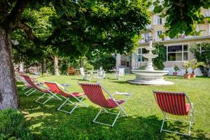 a group of chairs sitting in the grass near a fountain at Hotel Regina in Wengen