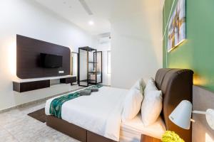 a bedroom with a bed with a tv on the wall at Cenang Rooms With Pool by Virgo Star Resort in Pantai Cenang