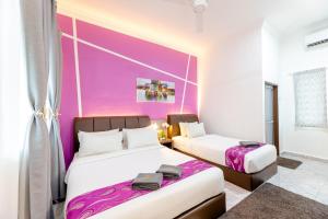 two beds in a room with a purple wall at Cenang Rooms With Pool by Virgo Star Resort in Pantai Cenang