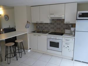 een keuken met witte kasten en een fornuis met oven bij Les Landes avec Terrasse et Jardin in Heuringhem