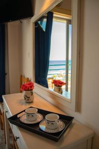 a kitchen counter with two cups and a window at De La Plage Hotel Koroni in Koroni